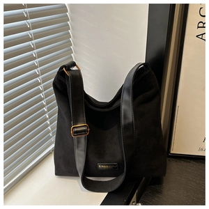 Close-up of black suede bucket bag with adjustable strap and golden metal buckle details