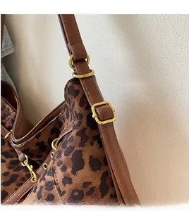 Detail of adjustable brown leather shoulder strap with golden buckle on leopard tote bag
