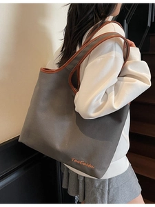 Large grey canvas tote bag with brown leather trim and shoulder strap shown on model
