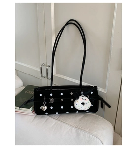 Detailed view of polka dot baguette bag with metal heart charm and donut plush toy