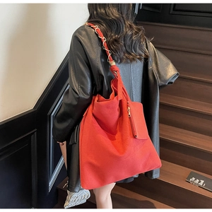 Détail du sac cabas rouge en daim avec chaîne métallique et fermeture éclair latérale