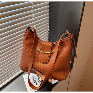 Close-up of caramel brown leather shoulder bag with elegant gold metal hardware detail