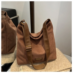 Detail view of brown matte suede hobo bag with adjustable strap and metal brand plate