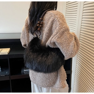 Detailed shot of fuzzy black faux fur shoulder bag with unique brown beaded strap