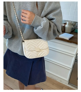 Detailansicht der weißen Stepptasche mit silberner Kette und Metallverschluss am Gurt