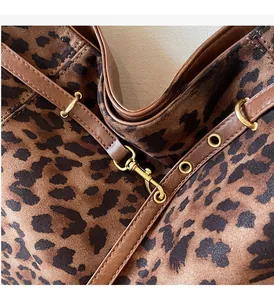 Detail of leopard print fabric with brown leather trim and golden metal hook hardware