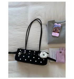 Flat lay of black polka dot shoulder bag with heart pendant and plush charm details