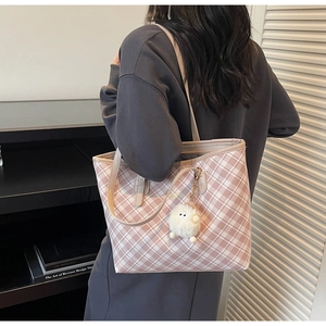 Λεπτομέρεια ροζ και λευκής καρό τσάντας με βελούδινο μπρελόκ και λογότυπο στο δέρμα
