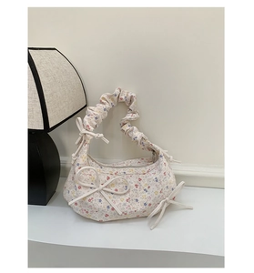 Détail du sac à main en toile florale avec poignée plissée et ornement de nœud chic
