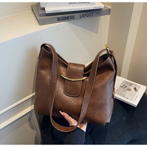 Close-up of vintage brown leather tote bag with elegant gold buckle and shoulder strap
