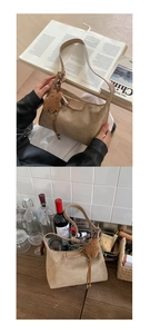 Détail du sac à épaule en daim kaki avec pendentif ours sur une surface en bois