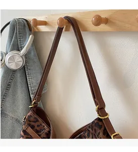 Detail of leopard print tote bag featuring brown leather strap and gold ring hardware