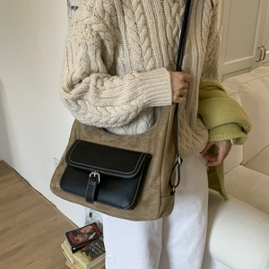 Detail of vintage suede shoulder bag featuring a black leather pocket and metal buckle