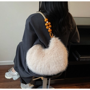 Detail of plush faux fur shoulder bag with wooden beaded rope strap on person