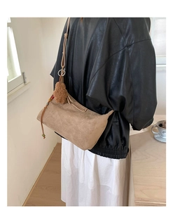 Détail d'un sac à bandoulière en daim marron clair avec pompon et franges en cuir