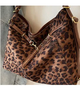 Close-up of leopard print tote bag with brown leather straps and gold metal hooks