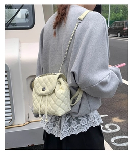 Dettaglio di un mini zaino in pelle trapuntata beige con catene e coulisse di perle