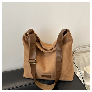Detail of dark brown suede tote bag with leather straps and golden metal buckles