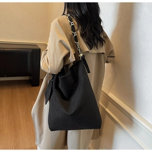 Détail d'un sac hobo en daim noir avec bandoulière classique en chaîne métallique tressée