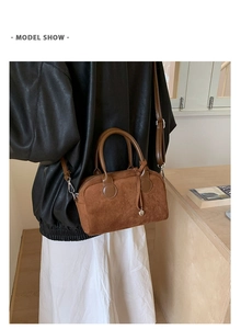 Detailed view of caramel suede pillow bag with a heart pendant and dual handles