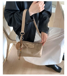 Détail du sac bandoulière en daim kaki avec pompon en peluche et breloques perlées