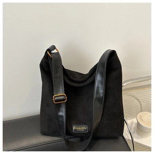 Detail of black tote bag with gold metal buckle and embossed leather brand tag