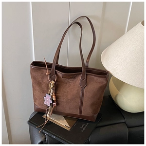 Vista dettagliata della borsa tote vintage marrone con ciondolo a orsetto e logo dorato