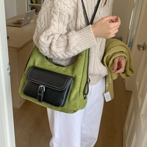 Close-up of vintage green dumpling bag with black flap and silver metal buckle on model