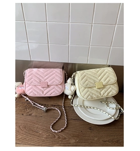 Detail von gesteppten Umhängetaschen in Rosa und Weiß mit Kettenriemen und Anhänger