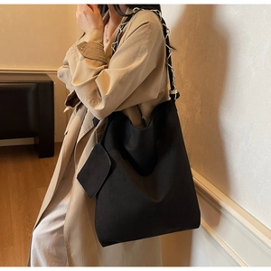 Détail du grand sac cabas noir avec chaîne dorée et petite pochette porté par le mannequin