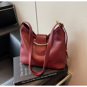 Detailed shot of dark red vintage shoulder bag with golden crescent clasp on art book