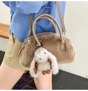 Detail of fuzzy brown faux fur handbag featuring a cute plush bunny charm and silver hardware