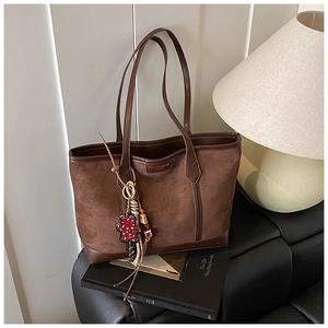Brown tote bag detail with fashion metal plaque and a red polka dot bear charm