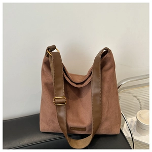 Detail of brown suede hobo bag featuring a wide shoulder strap and gold-tone hardware