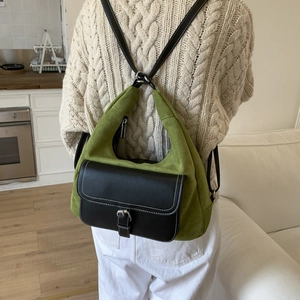 Detail of vintage green suede backpack showing contrast leather straps and white stitching