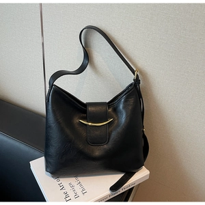 Detail of a black PU leather tote bag featuring a decorative gold crescent metal buckle