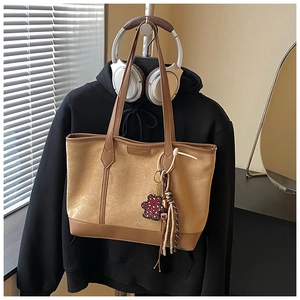 Detail of tan suede tote bag with leather straps and bear pendant on a hanger