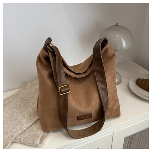 Detail of caramel suede tote bag featuring a leather brand tag and vintage texture