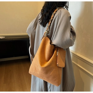 Gros plan d'un sac cabas en daim caramel avec bandoulière chaîne et pochette assortie