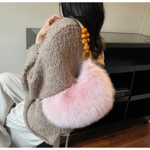 Close-up of pink faux fur crescent bag with orange beaded strap on a female model