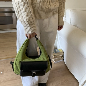 Detail of green suede dumpling bag with black leather pocket and silver buckle accent