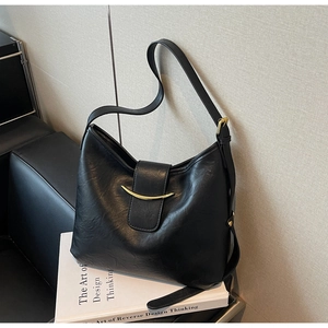 Detailed view of black hobo bag with pebbled leather texture and golden half-moon buckle