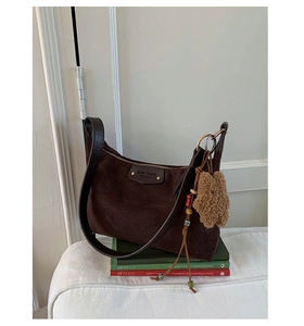 Détail du sac hobo en daim marron foncé avec bandoulière en cuir et charm ours mignon