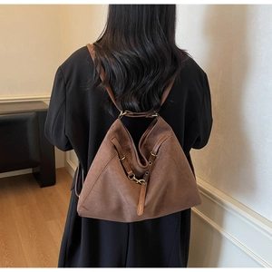Brown suede tote bag with drawstring detail shown on shoulder for size reference