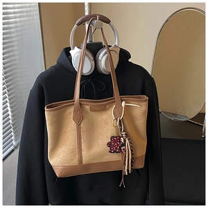 Detail of vintage tote bag with suede texture, metallic logo, and leopard bear charm