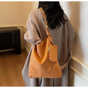 Détail d'un sac cabas en daim caramel avec bandoulière chaîne et pochette sur mannequin