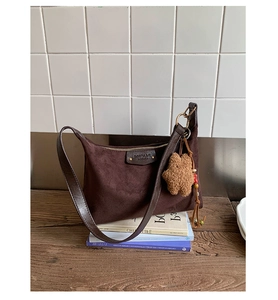 Gros plan d'un sac bandoulière en daim marron avec pendentif étoile sur une table