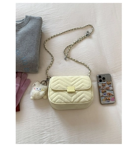 Detailansicht der beige Wellen-Stepptasche mit Plüschkatzen-Anhänger und Kettenriemen