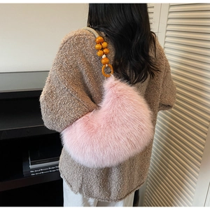 Pink faux fur handbag with beaded strap detail shown on a model in a cozy setting