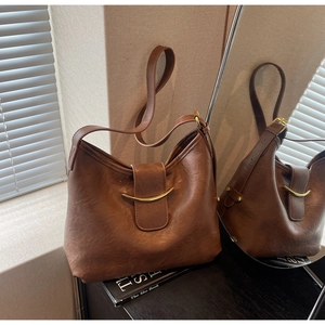 Detail of vintage brown leather bag featuring a polished gold crescent moon metal buckle